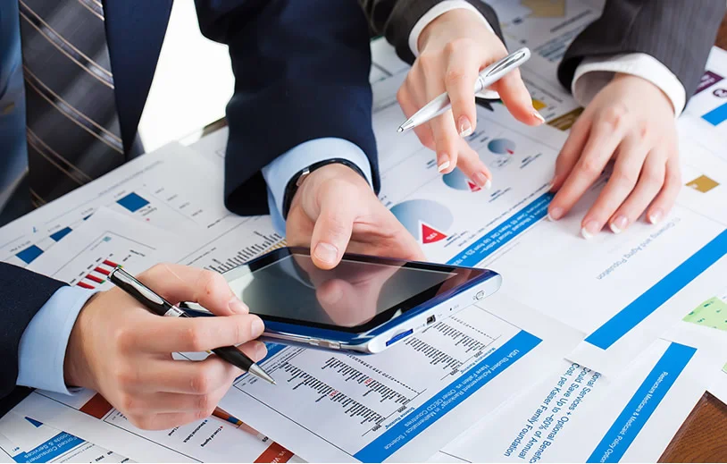 Two people reviewing financial charts and a tablet