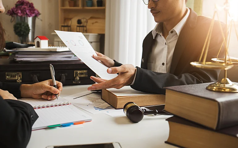 Lawyer advising a client beside law books, scales and a gavel