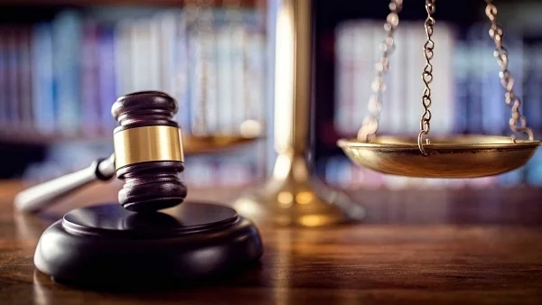 Gavel and brass scales of justice on a wooden desk