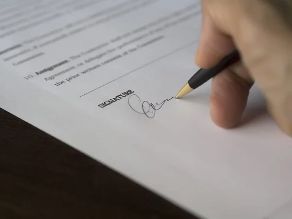 Hand signing a contract on the signature line