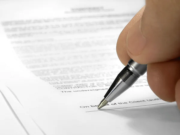 Hand signing a document with a pen