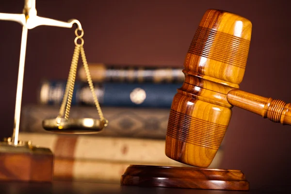 Wooden gavel and brass scales of justice in front of law books
