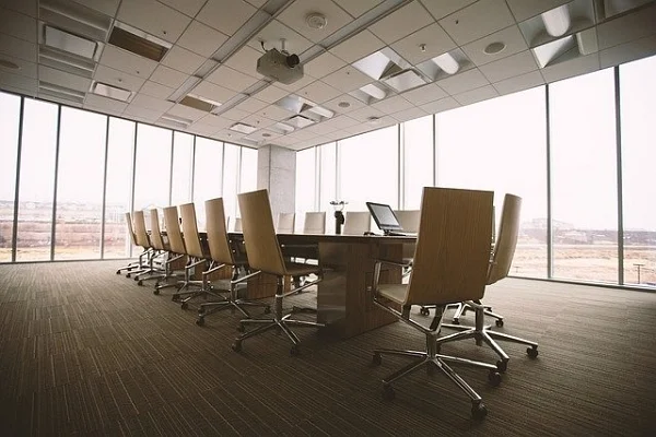 Empty conference room with a long table, office chairs and floor-to-ceiling windows