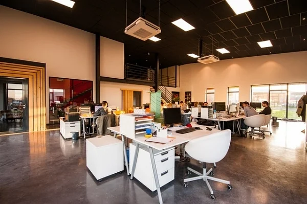 Open-plan office with white desks and people working at computers
