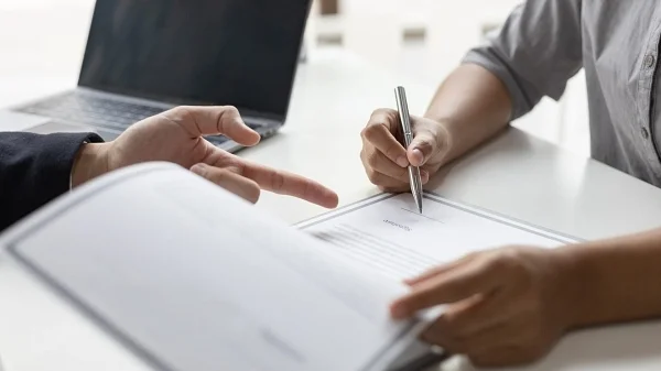 Two people reviewing and signing a document at a desk
