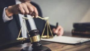 Gavel and scales of justice on a desk beside a lawyer