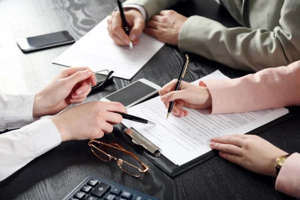 Two people reviewing and signing paperwork at a desk