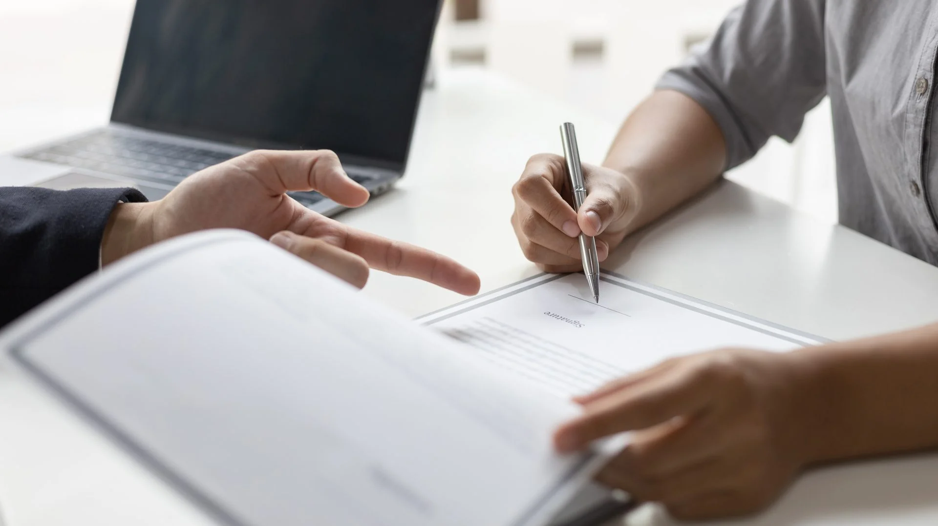 Two people reviewing and signing a document at a desk
